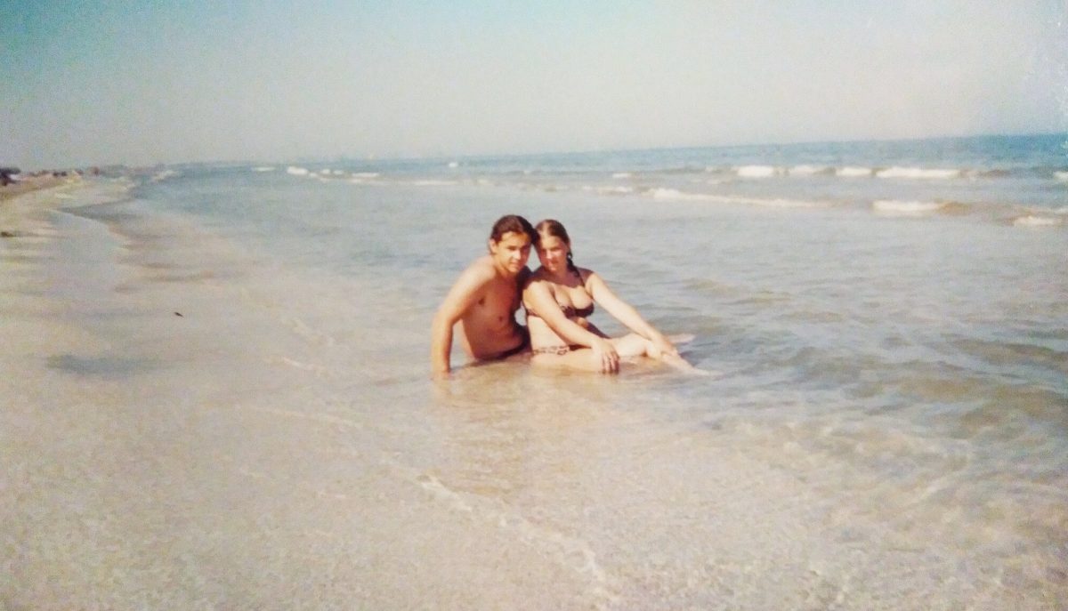 Fiatal pár ül a a tengerparton, a sekély vízben